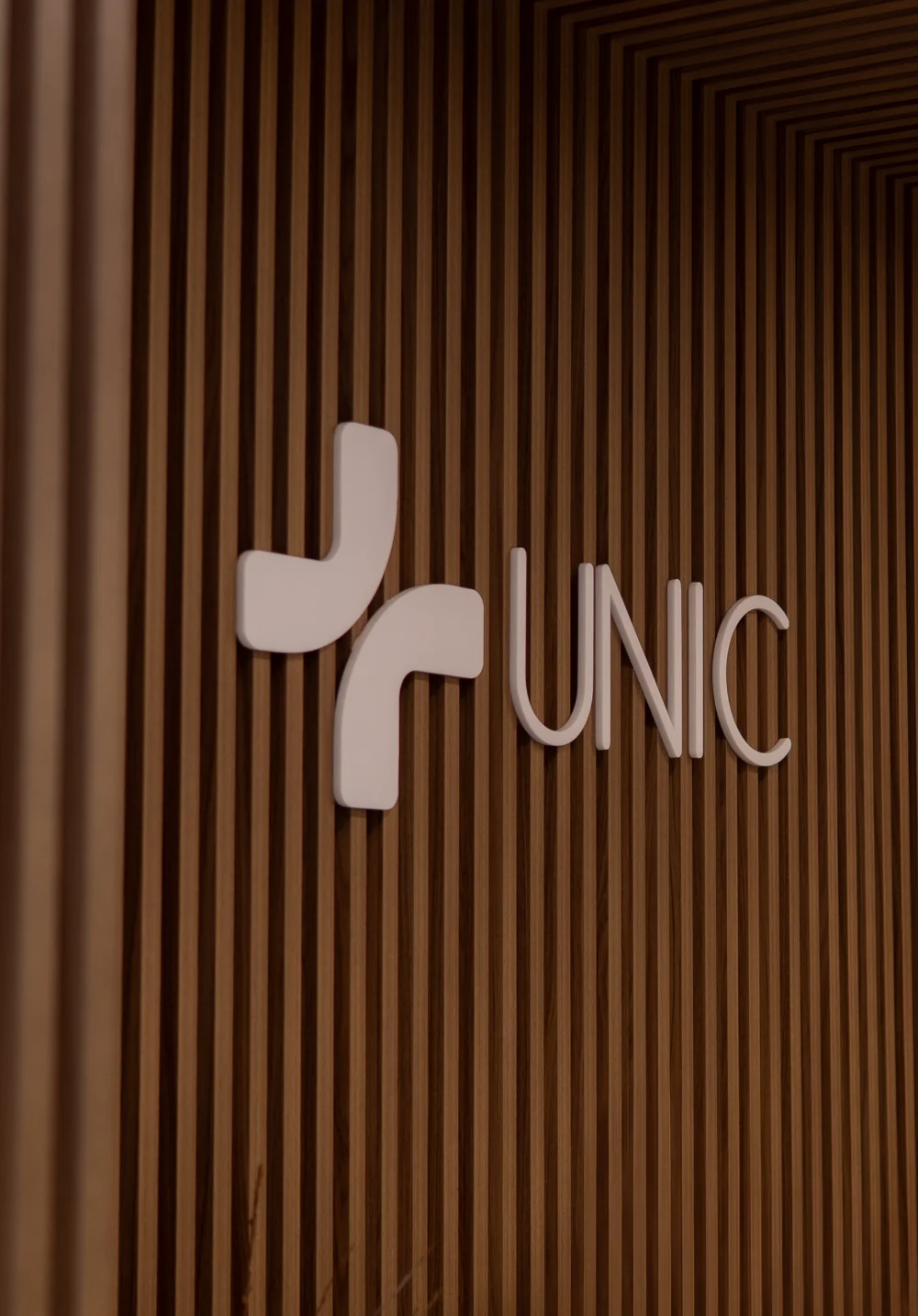 Marca do Hospital Unic aplicada em painel ripado de madeira na área interna
